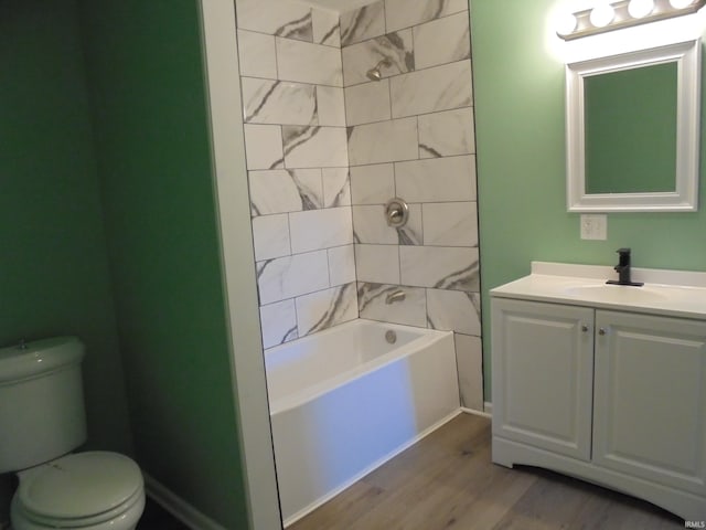 full bathroom featuring vanity, wood-type flooring, tiled shower / bath combo, and toilet