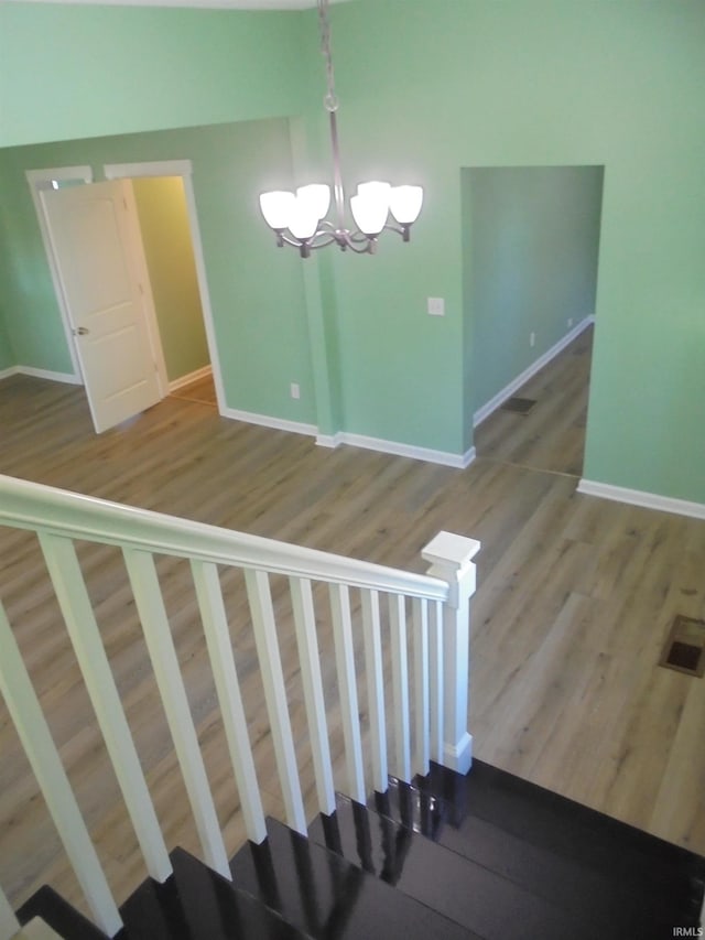 staircase featuring hardwood / wood-style floors and a notable chandelier