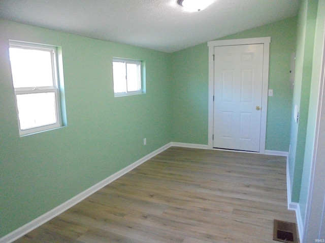 spare room with light wood-type flooring and vaulted ceiling