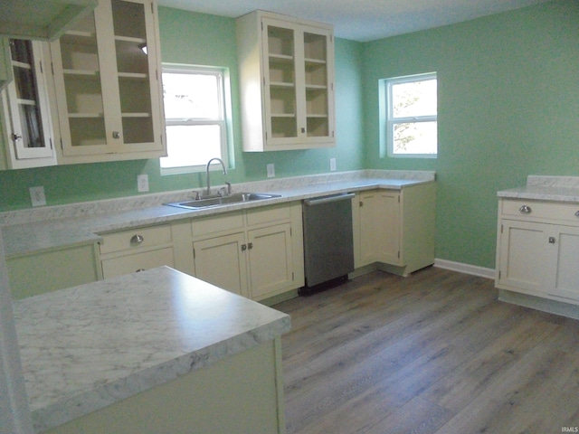 kitchen with stainless steel dishwasher, white cabinetry, light wood-type flooring, and sink