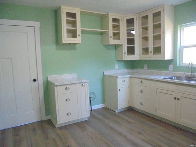 kitchen featuring light wood-type flooring, white cabinetry, and sink