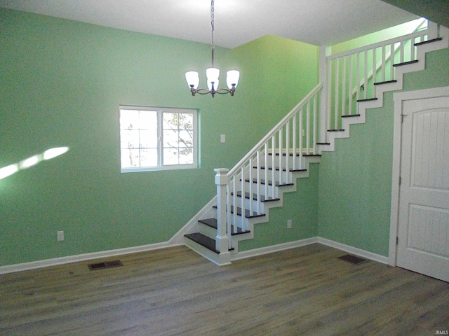 stairway featuring hardwood / wood-style flooring and an inviting chandelier