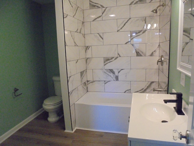 full bathroom featuring hardwood / wood-style floors, tiled shower / bath combo, toilet, and sink