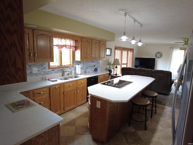 kitchen with pendant lighting, black appliances, sink, decorative backsplash, and a breakfast bar area