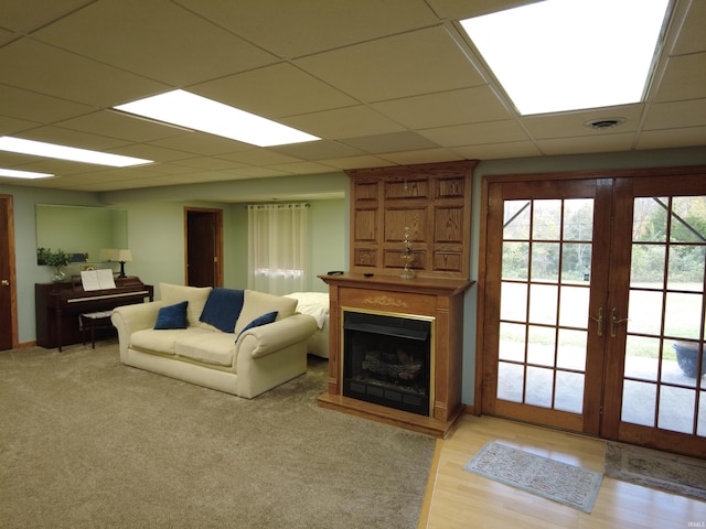 living room with a paneled ceiling, french doors, and light hardwood / wood-style floors