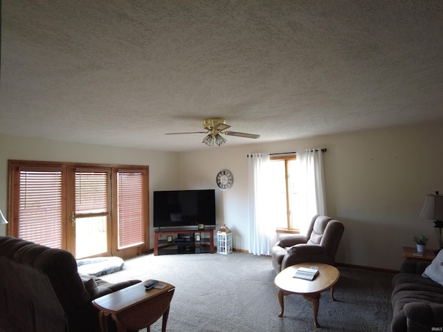 carpeted living room featuring ceiling fan and a textured ceiling