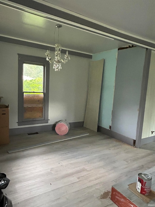 unfurnished room featuring a chandelier and light hardwood / wood-style flooring