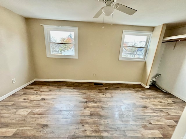 spare room with ceiling fan, a healthy amount of sunlight, and light hardwood / wood-style floors