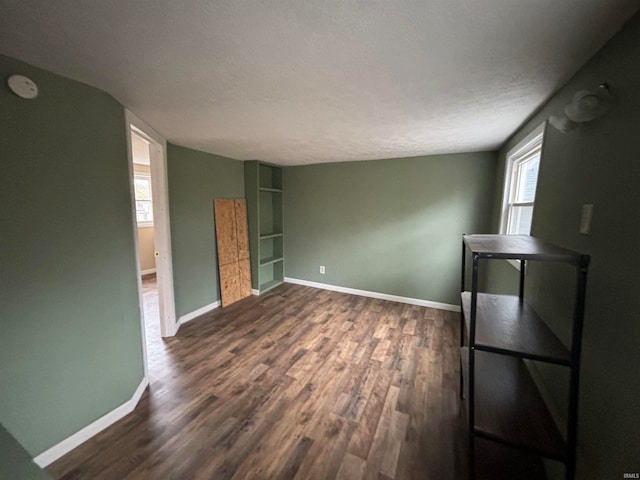 spare room featuring vaulted ceiling, plenty of natural light, a textured ceiling, and dark hardwood / wood-style floors