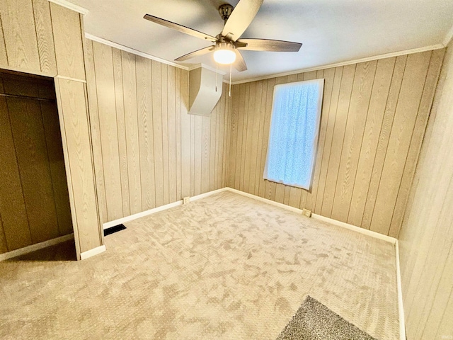 unfurnished bedroom with carpet, ceiling fan, and wooden walls