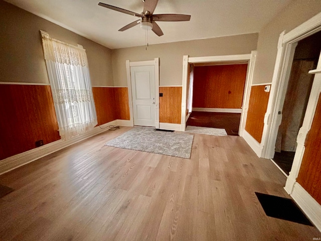 interior space featuring light hardwood / wood-style floors, ceiling fan, and wooden walls