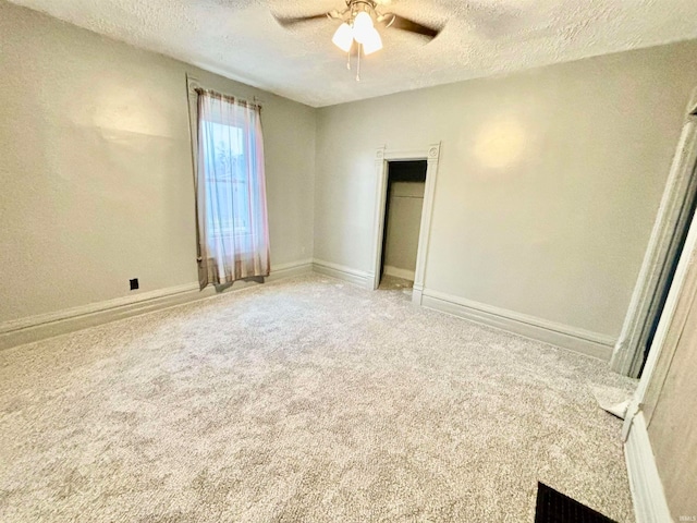 unfurnished bedroom with a textured ceiling, carpet floors, and ceiling fan