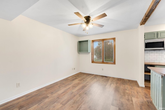 spare room with beamed ceiling, light hardwood / wood-style floors, and ceiling fan