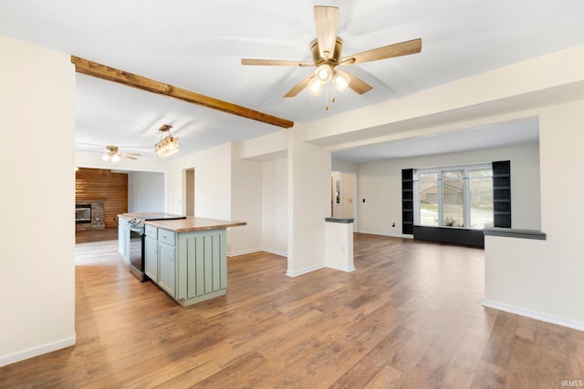 kitchen featuring light wood-type flooring, ceiling fan, a fireplace, a center island, and green cabinets