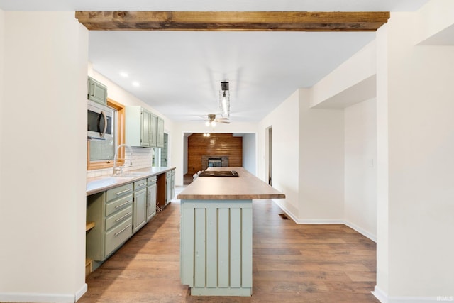 kitchen with backsplash, sink, green cabinetry, ceiling fan, and light wood-type flooring