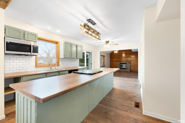 kitchen featuring sink, dark hardwood / wood-style flooring, backsplash, a kitchen island, and green cabinetry