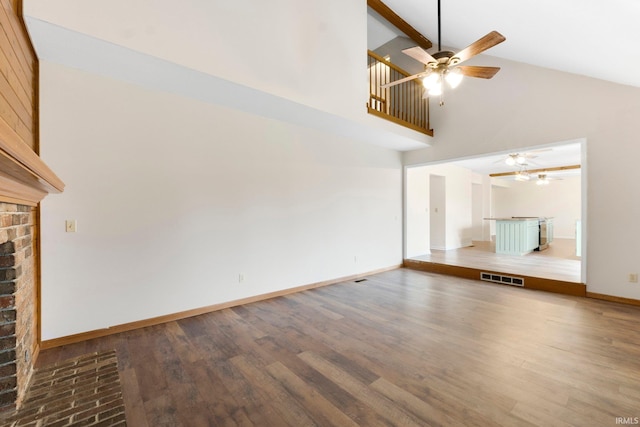 unfurnished living room featuring hardwood / wood-style flooring, ceiling fan, high vaulted ceiling, and a brick fireplace