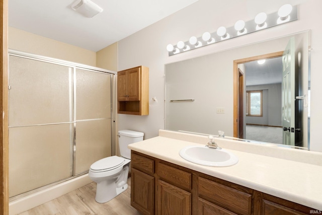 bathroom featuring hardwood / wood-style floors, vanity, an enclosed shower, and toilet