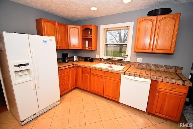 kitchen with white appliances, sink, a textured ceiling, tile counters, and light tile patterned flooring