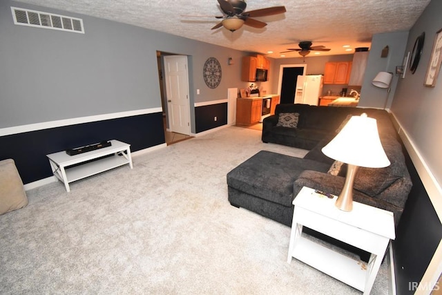 living room featuring ceiling fan, a textured ceiling, and light carpet