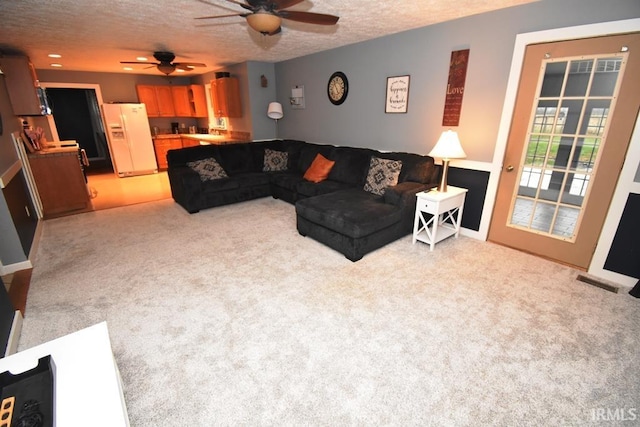 carpeted living room with ceiling fan and a textured ceiling