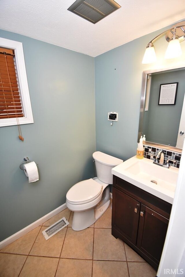 bathroom featuring toilet, vanity, tile patterned floors, and backsplash