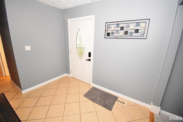 foyer with light tile patterned floors and a textured ceiling