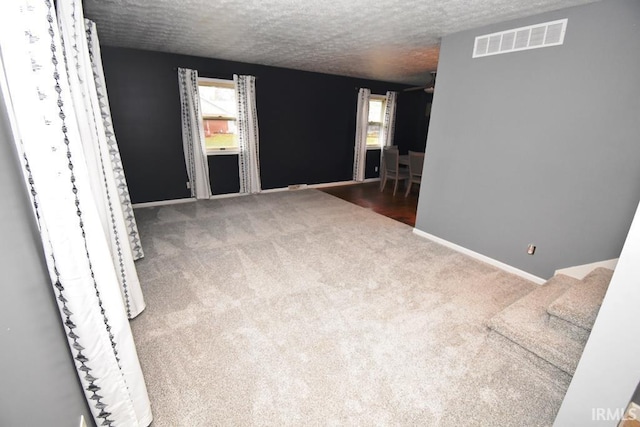 carpeted spare room featuring a textured ceiling and a healthy amount of sunlight