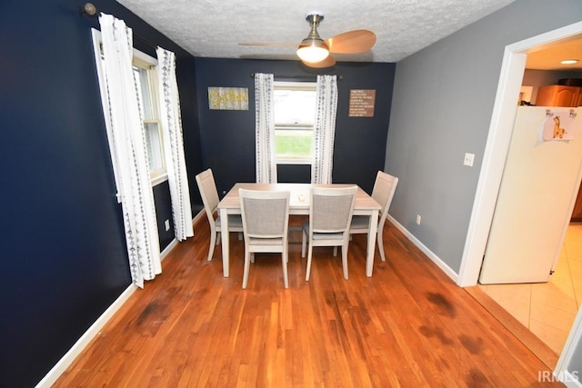 unfurnished dining area featuring wood-type flooring, a textured ceiling, and ceiling fan