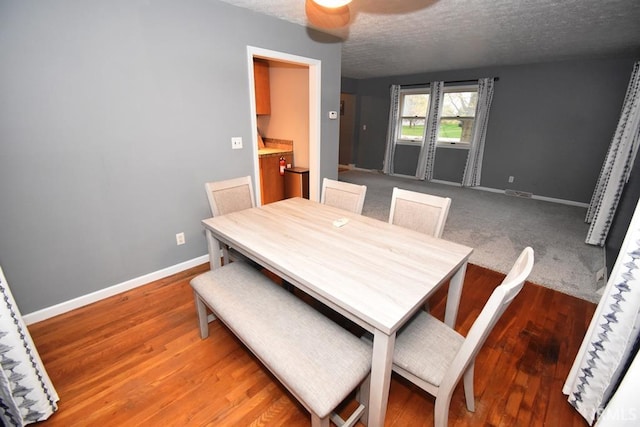 dining area with ceiling fan, wood-type flooring, and a textured ceiling