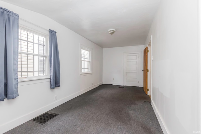 spare room featuring dark colored carpet