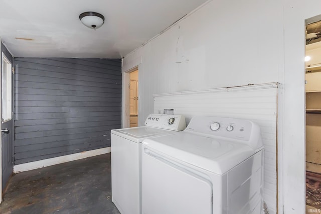 clothes washing area with washer and clothes dryer and wooden walls