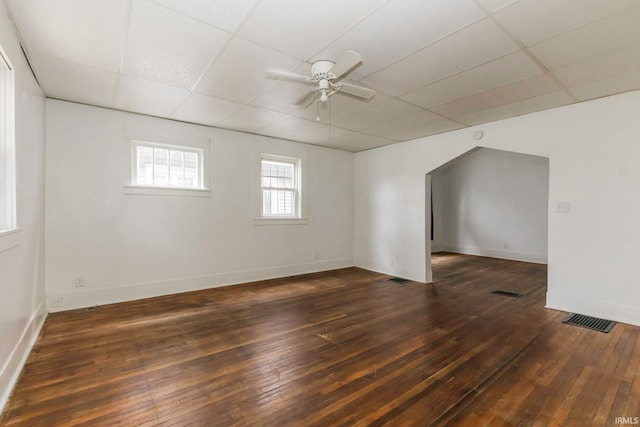 empty room featuring a paneled ceiling, ceiling fan, and dark wood-type flooring