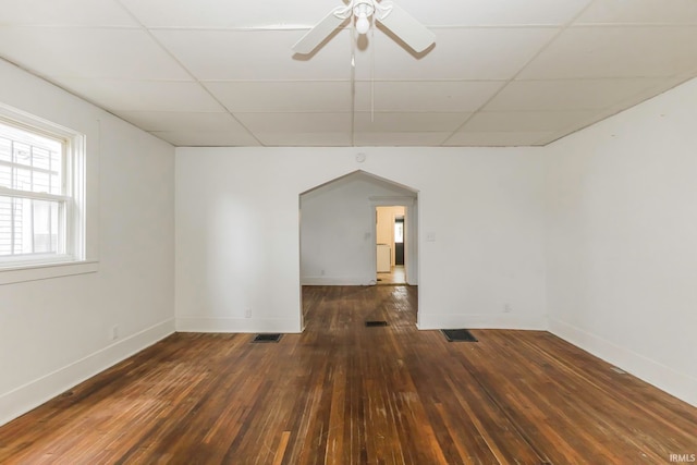 spare room featuring a drop ceiling, ceiling fan, and dark wood-type flooring