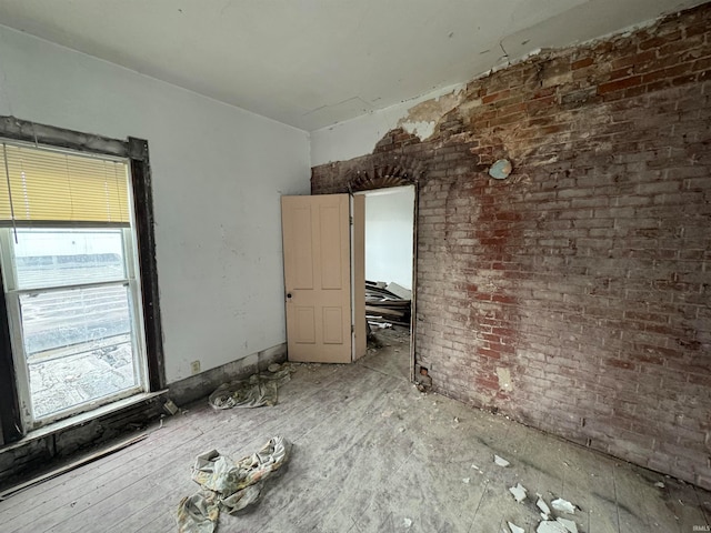 unfurnished room featuring brick wall