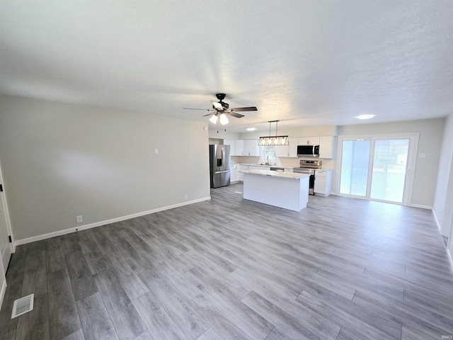 unfurnished living room featuring a textured ceiling, light hardwood / wood-style flooring, and ceiling fan