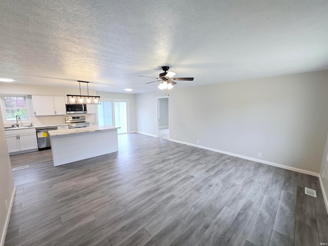 kitchen featuring pendant lighting, wood-type flooring, white cabinetry, and appliances with stainless steel finishes