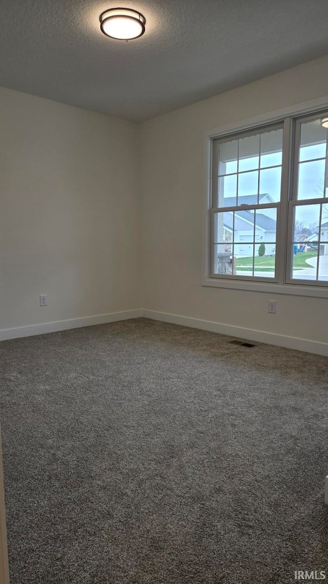 carpeted empty room featuring a textured ceiling