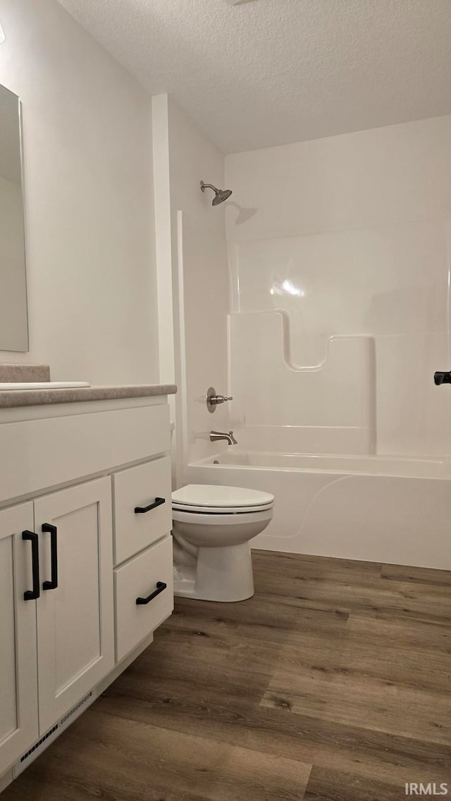 full bathroom with hardwood / wood-style flooring, vanity, toilet, and a textured ceiling