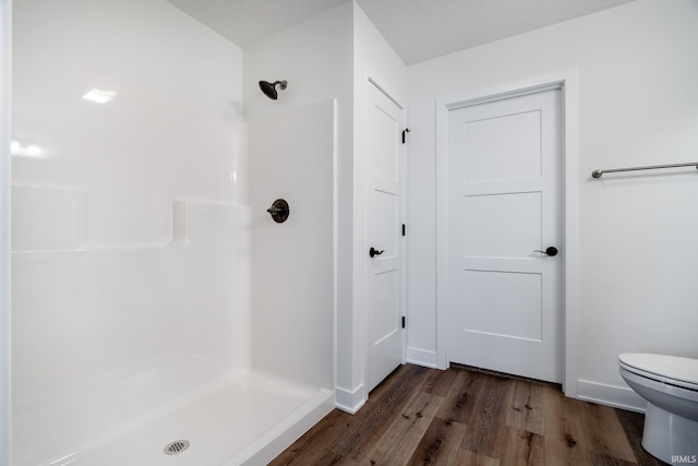 bathroom with hardwood / wood-style floors, toilet, and walk in shower