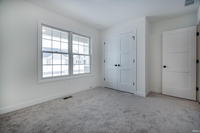 unfurnished bedroom featuring a closet and light colored carpet