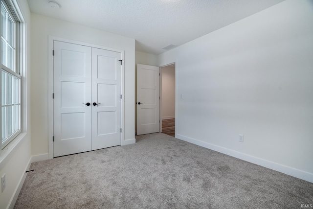 unfurnished bedroom featuring light colored carpet and a closet