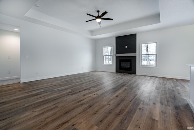 1173 Olympiada Knl, Fort Wayne, IN 46845 - unfurnished living room with a tray ceiling, dark wood-style floors, a ceiling fan, baseboards, and a fireplace