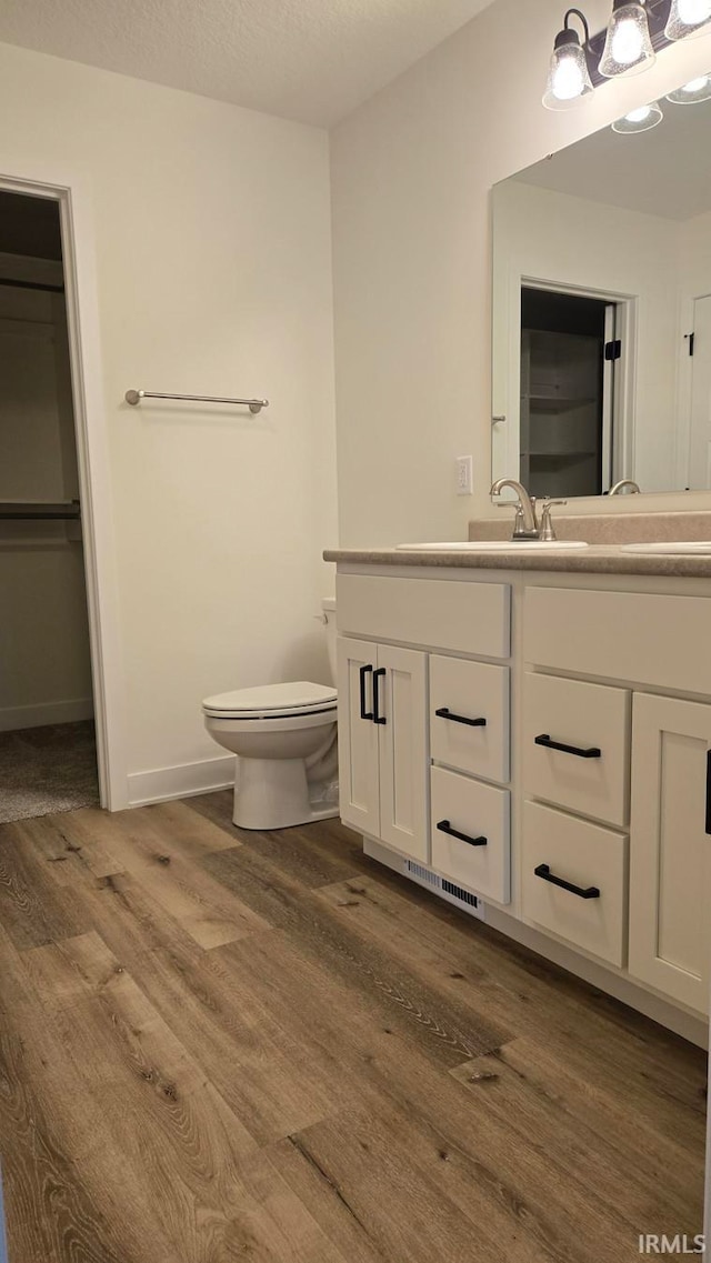 bathroom featuring vanity, wood-type flooring, a textured ceiling, and toilet