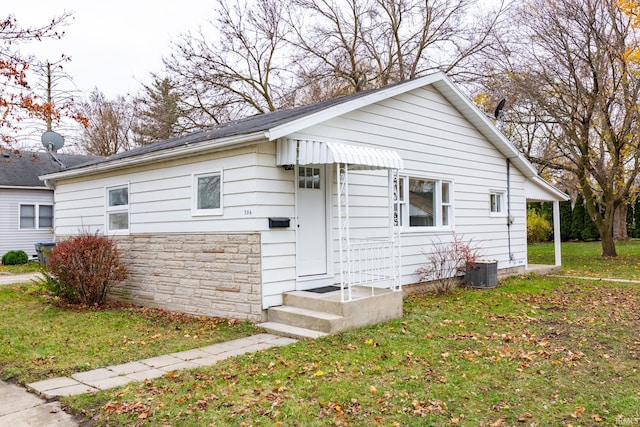 bungalow-style house featuring central air condition unit and a front lawn