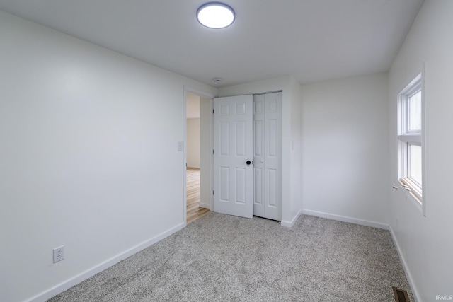 unfurnished bedroom with light carpet and a closet