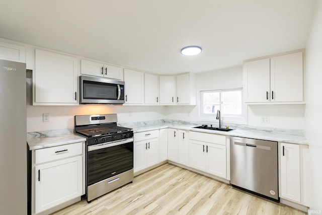 706 N Main St, Nappanee, IN 46550 - kitchen with stainless steel appliances, a sink, light wood-style flooring, and white cabinets