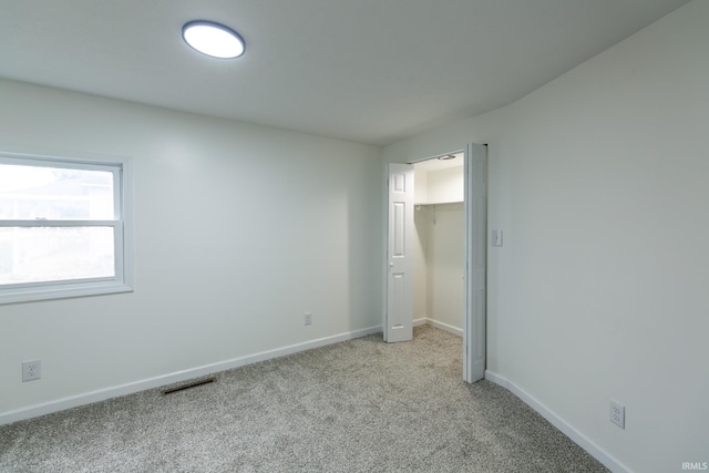 unfurnished bedroom featuring light colored carpet and a closet