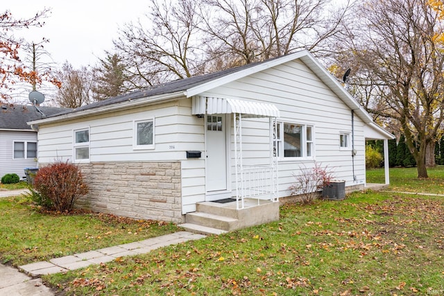 706 N Main St, Nappanee, IN 46550 - view of home's exterior featuring a yard, stone siding, and central air condition unit