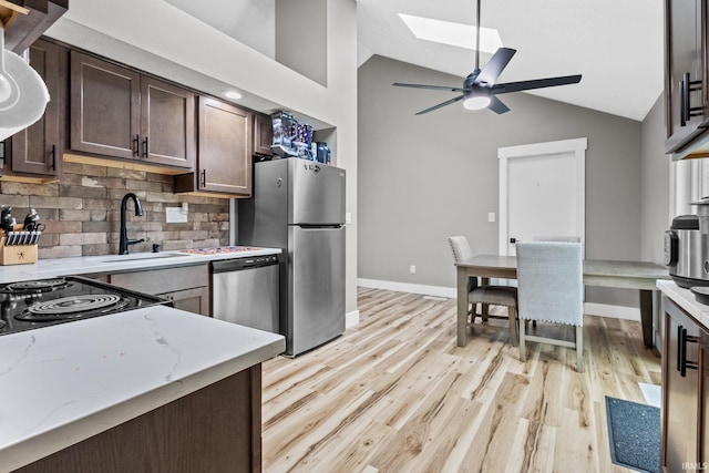 kitchen featuring dark brown cabinetry, light stone counters, stainless steel appliances, and light wood-type flooring